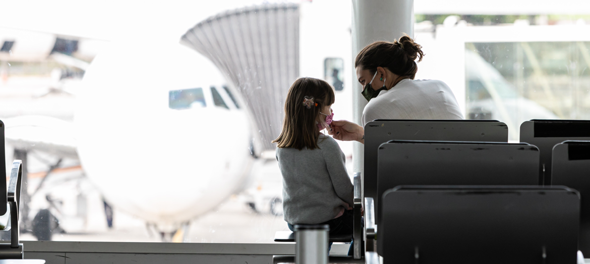 Mãe e filha usando mascaras sentadas no aeroporto